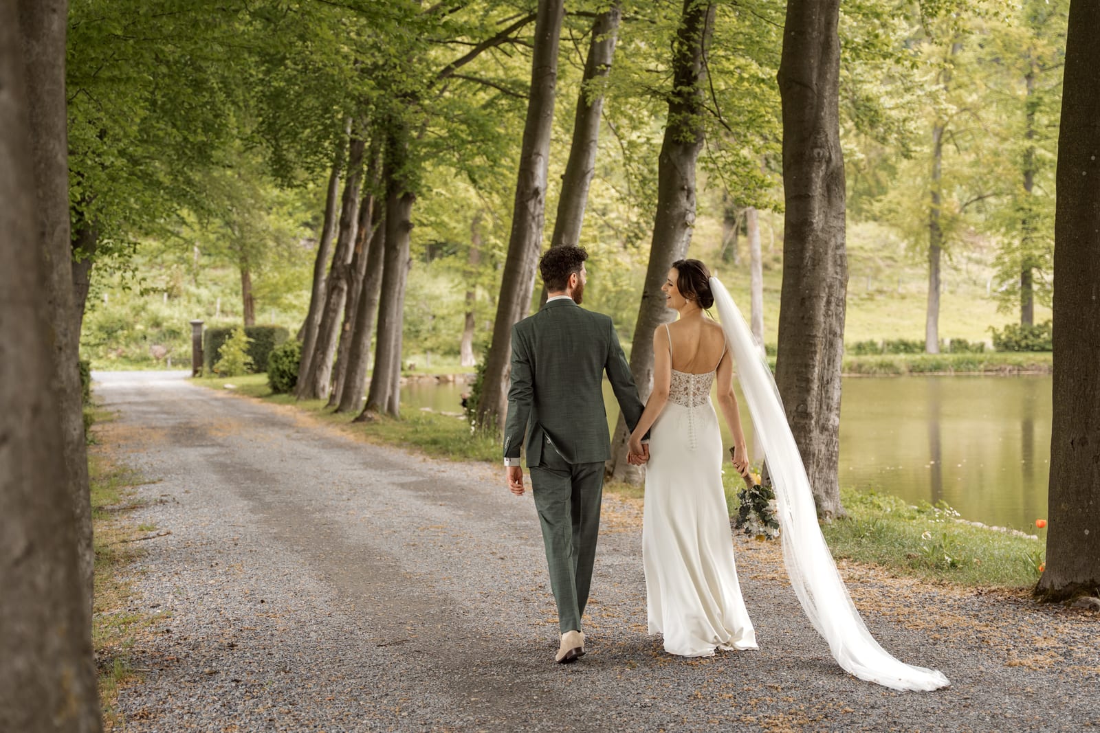 Susan en Maarten lopen hand in hand door een lange bomenlaan, het late licht valt tussen de stammen door