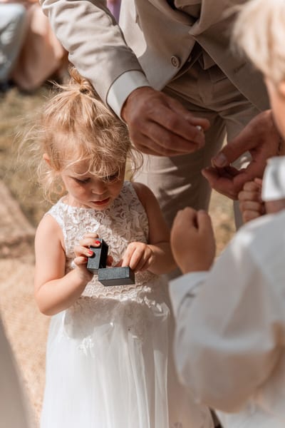 Een jong bruidsmeisje opent voorzichtig het doosje met de trouwringen van Bert en Verena