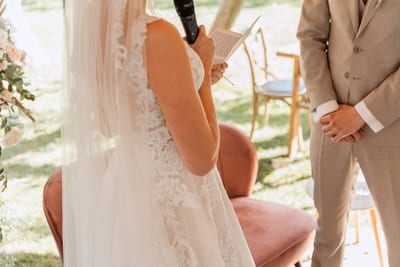 Esmee leest met microfoon haar geloften voor terwijl Danny tegenover haar staat tijdens de buitenceremonie