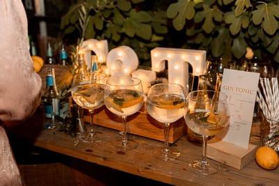 Glazen gin-tonic met garnering staan klaar op de houten bar voor de lichtletters op het feest van Danny en Esmee