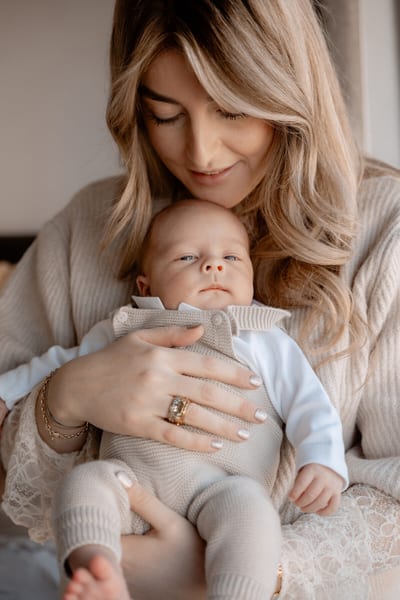 Moeder buigt zich liefdevol over haar pasgeboren baby, die met open oogjes in haar armen ligt