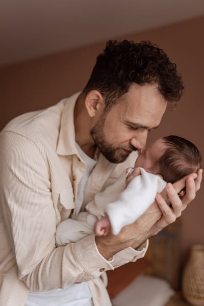 Vader houdt zijn pasgeboren baby vlak voor zijn gezicht en drukt zijn neus zachtjes tegen het snoetje van het kind